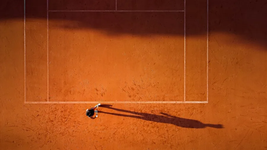 Athletic player executing sliding movement on professional tennis court during match play