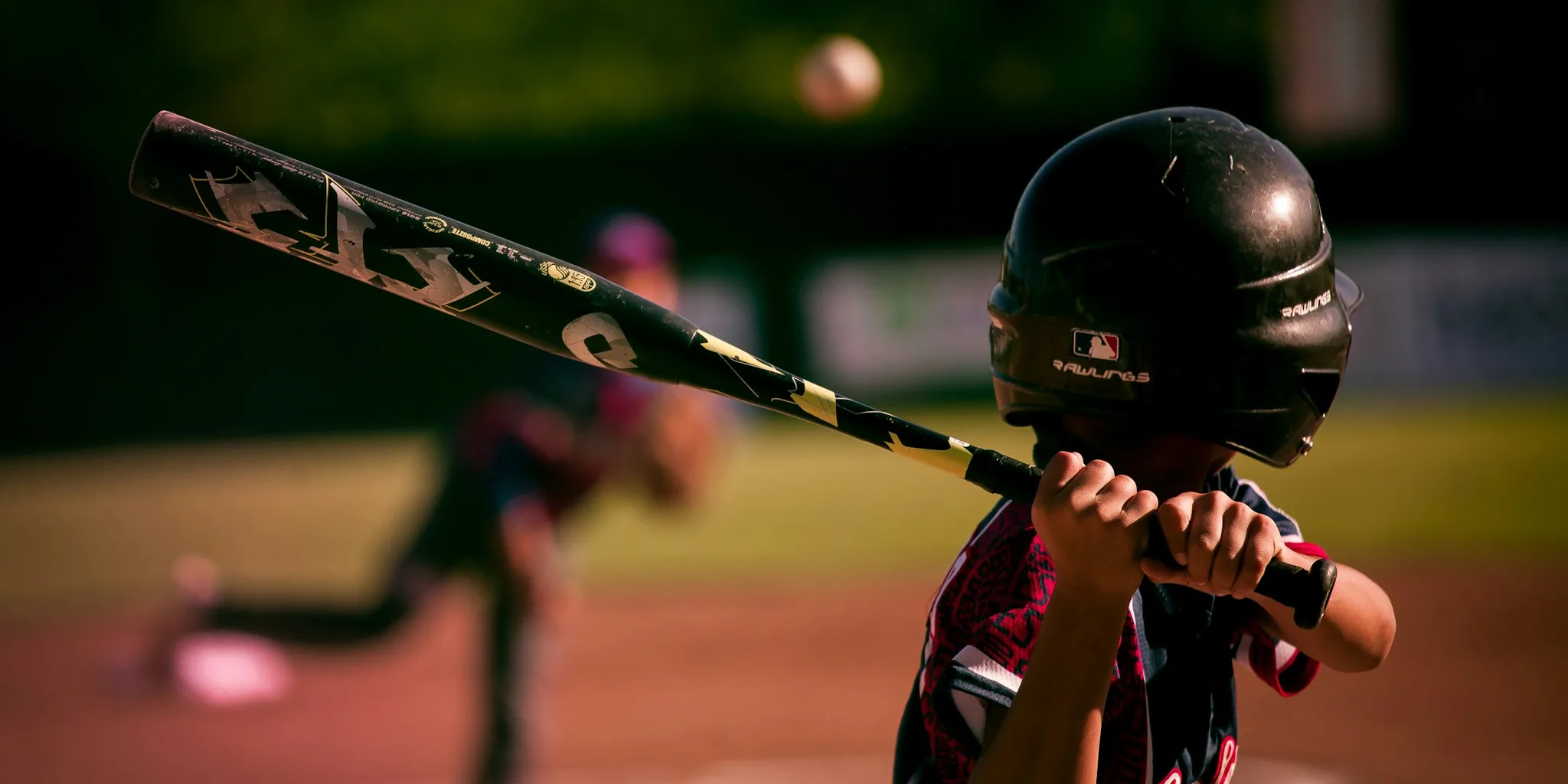 Baseball player mid-swing during batting practice on field with natural sunlight