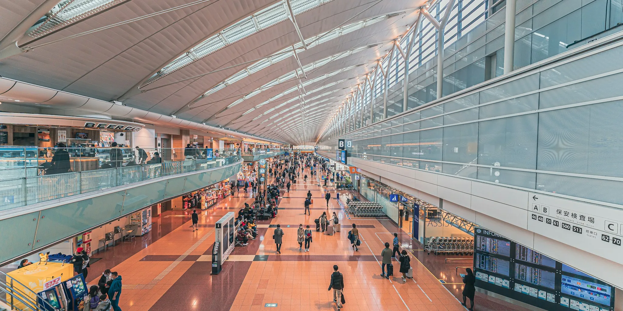 Business traveler pulling compact carry-on luggage through busy airport terminal with natural light