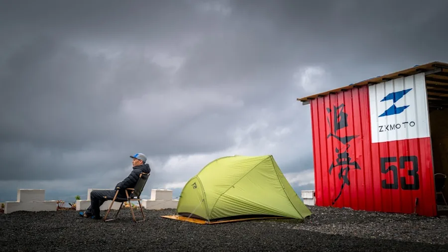Camper relaxing in chair on uneven outdoor ground during hiking trip