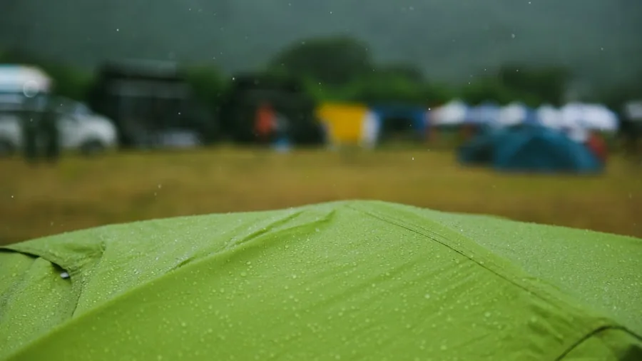 Camping tent during heavy rainfall with water droplets on fabric, demonstrating weatherproofing in stormy conditions