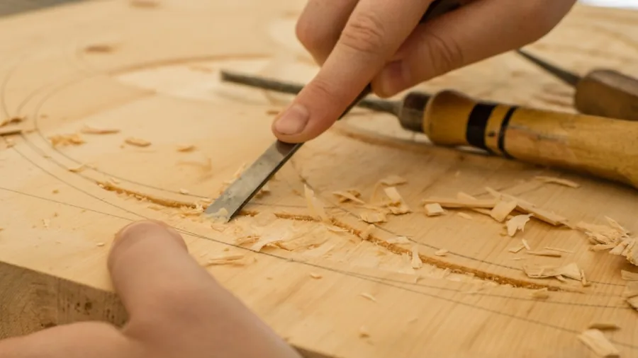 The 12 Best Nail Guns 4 Carpenter making fine adjustments to power tool settings on wooden workpiece during construction project