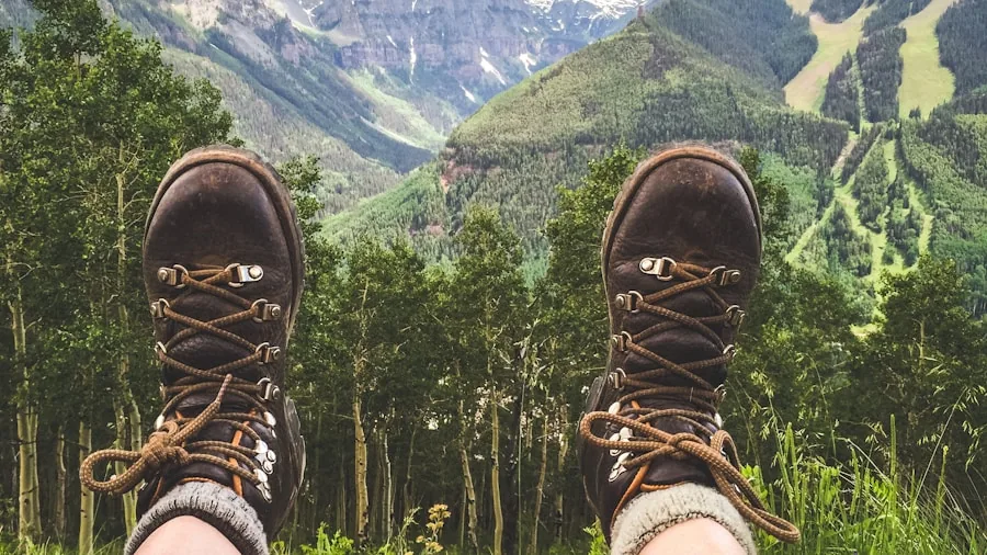 Close-up of a hiker examining and fitting hiking boots while sitting outdoors on a trail
