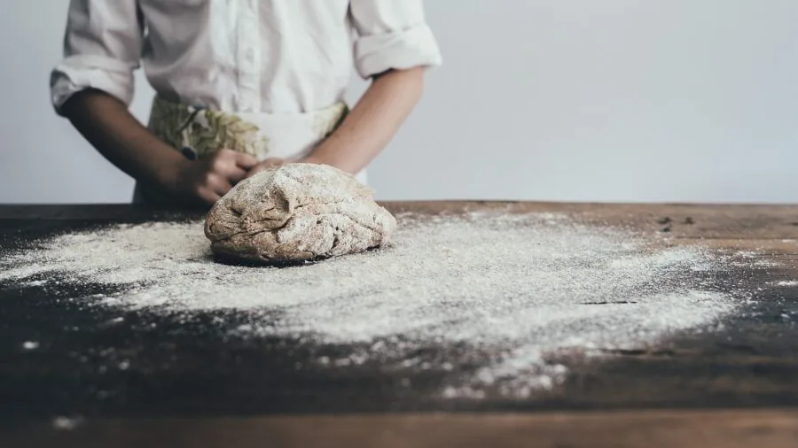 The %product_count% Best Stand Mixers 4 Close-up of baker's hands kneading bread dough on a wooden surface in a home kitchen