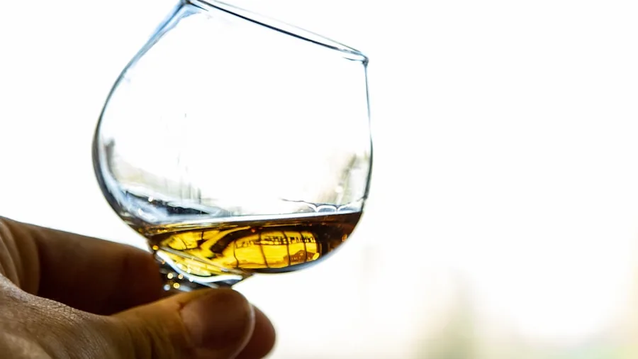 Close-up of crystal whiskey glass held up to light showing amber liquid and clarity