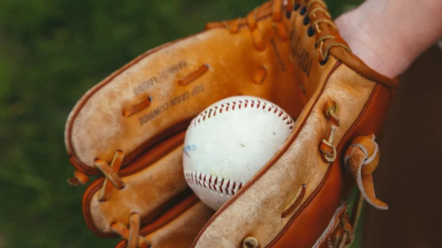 Close-up of hands inspecting worn leather baseball glove texture and durability