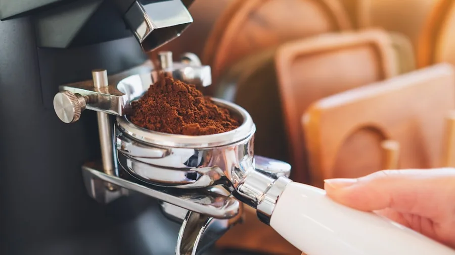 Close-up of someone using an electric burr grinder with freshly roasted coffee beans in natural kitchen light