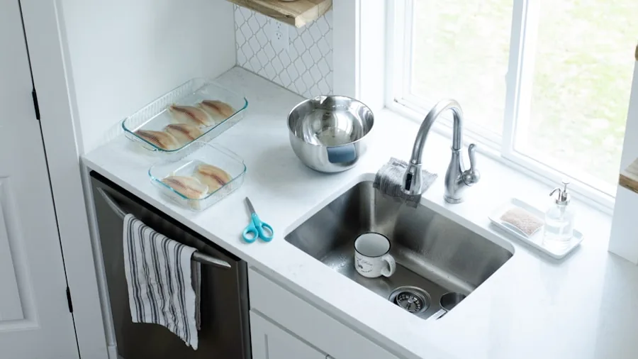 Close-up of stainless steel kitchen sink being cleaned and maintained under running water