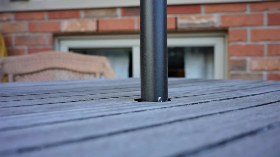 Close-up of weighted umbrella base on patio deck with garden furniture in background