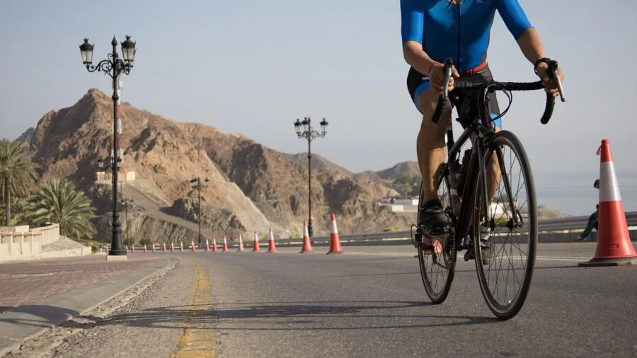 Cyclist riding uphill on mountain road during warm sunny day with focus on comfort and airflow