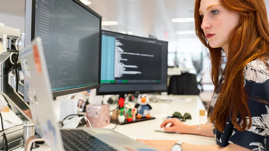 Developer's hands typing on keyboard at wooden desk with laptop and notebook