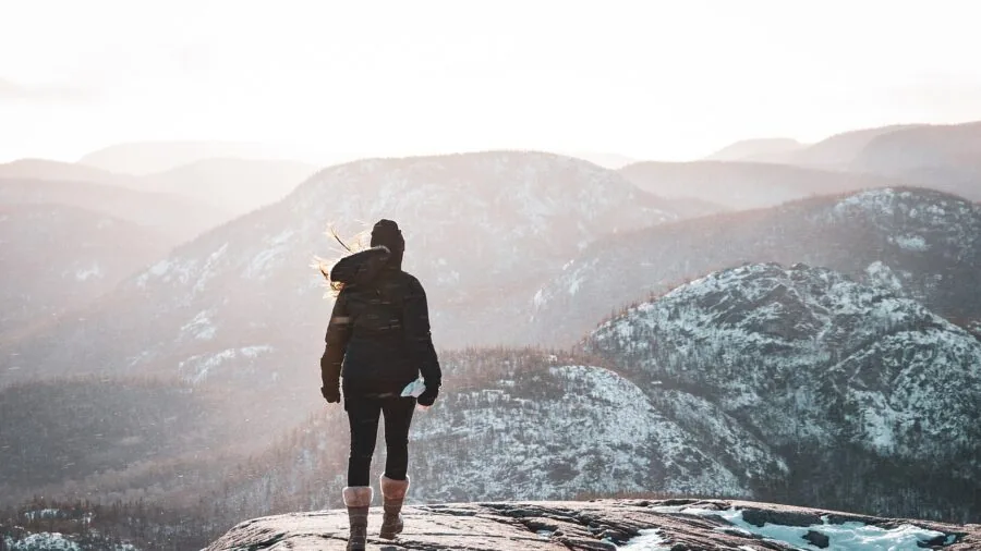 Female hiker crossing stream with waterproof boots on mountain trail