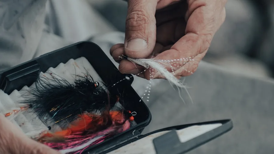 Fisherman inspecting a fishing lure by the water, checking its durability and condition before casting