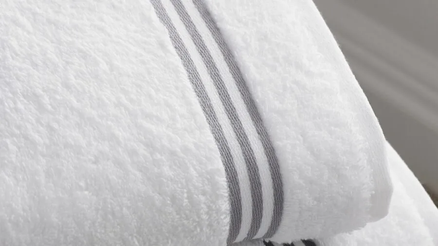 Fluffy cotton towels folded on wooden shelf in minimalist bathroom setting