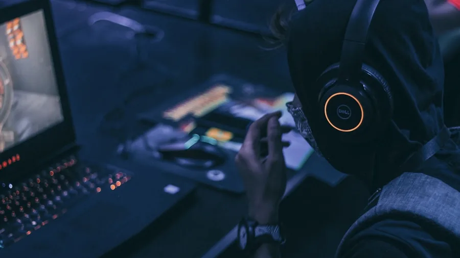 Focused gamer wearing headphones at computer setup, concentrating on screen during extended gaming session