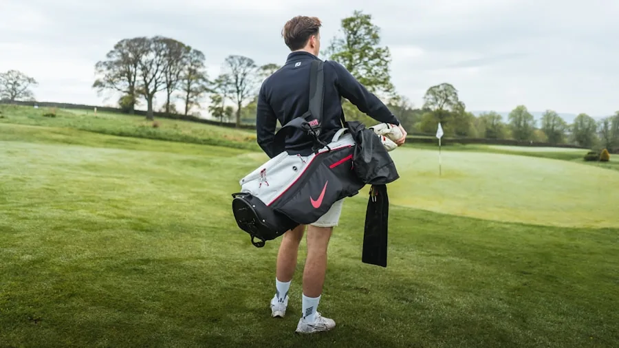 Golfer carefully arranging golf clubs in organized divider bag before round