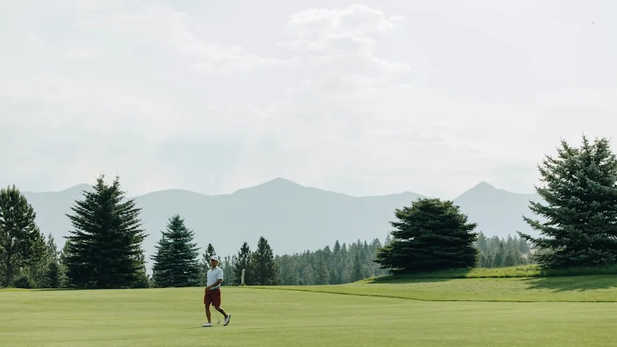 Golfer carrying stand bag while walking across green fairway during round of golf