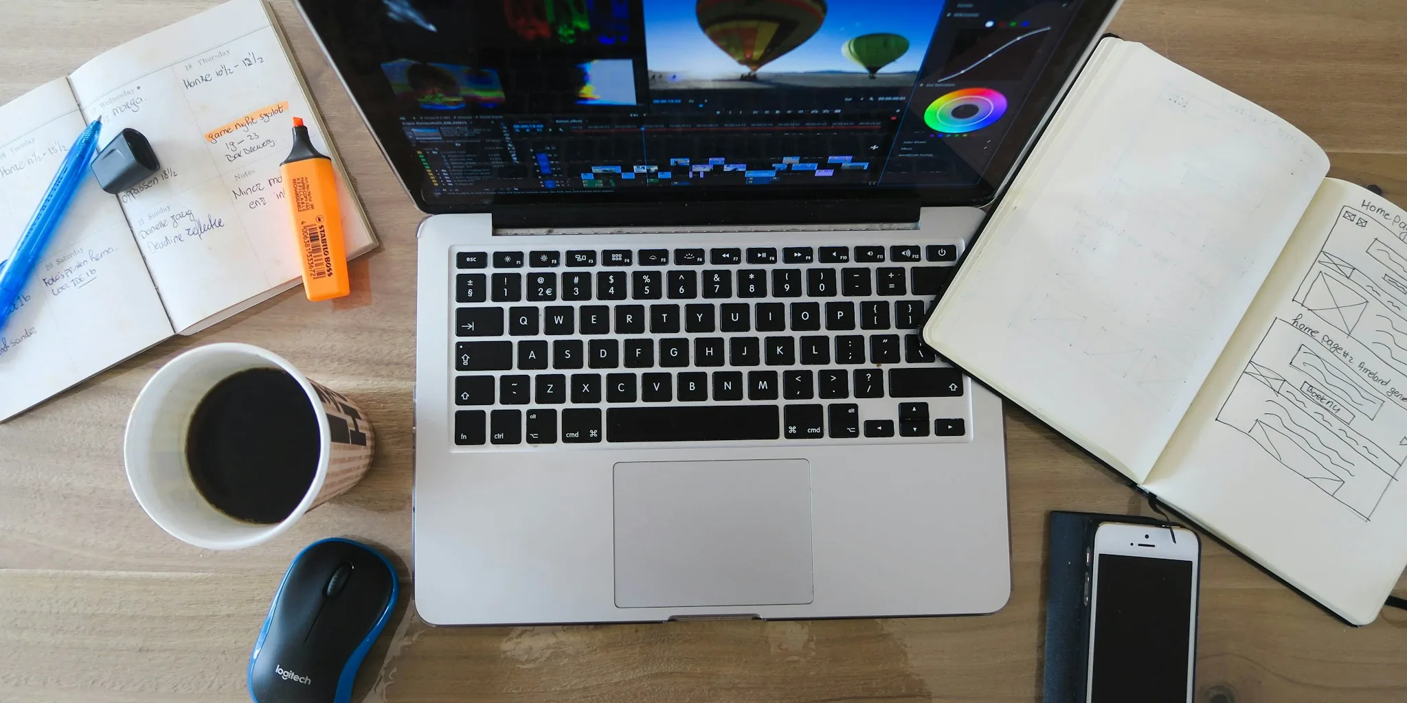 Graphic designer working on laptop at creative desk with design tools and natural lighting
