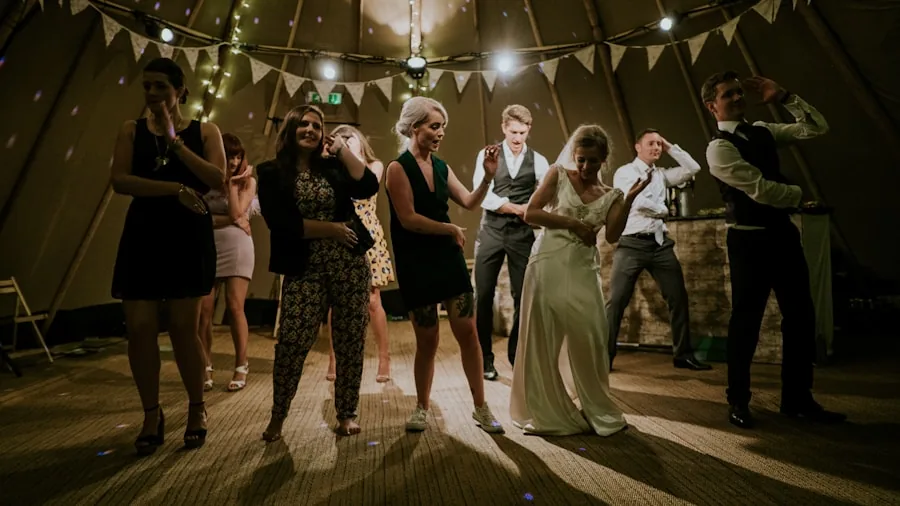 Group of friends dancing together at an indoor party with colorful ambient lighting