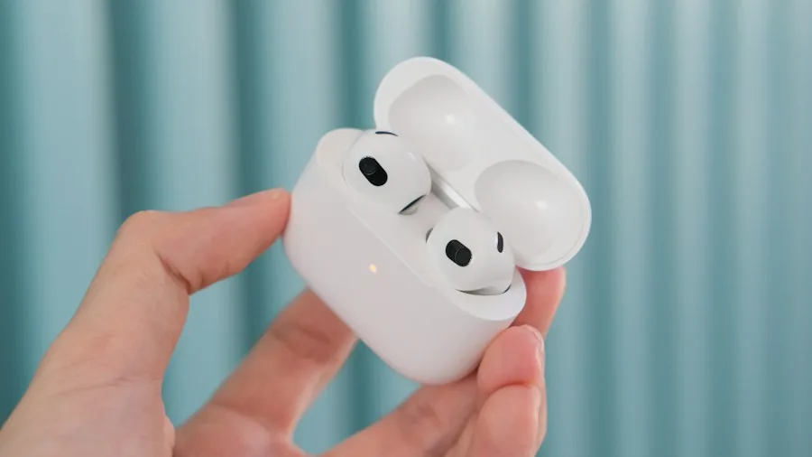 Apple AirPods 5 Launch: What Shoppers Should Know About the Pricing Shake-Up 2 hand holding earbuds with charging case