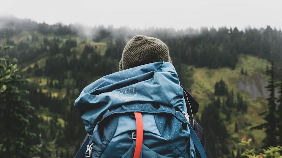 Hiker arranging gear and supplies inside backpack on outdoor trail with natural landscape background