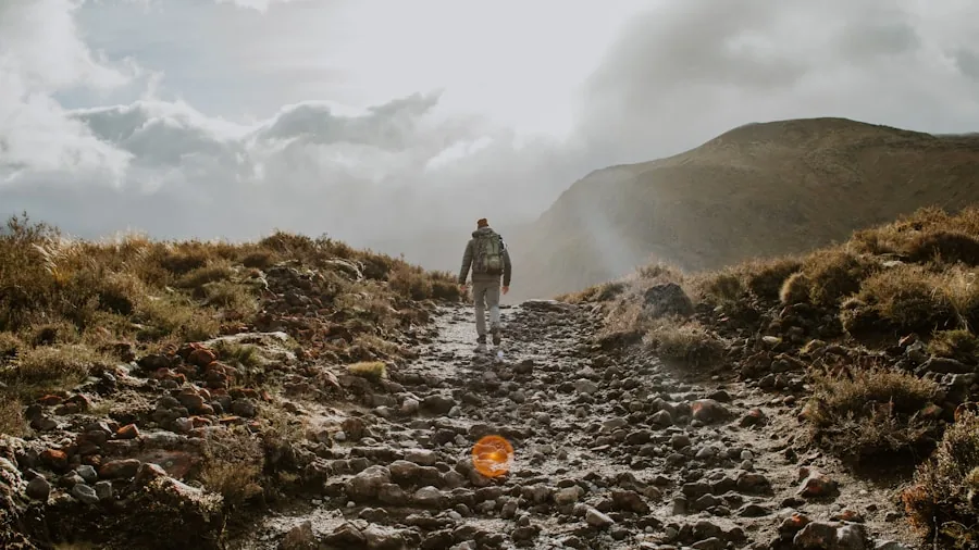 Hiker walking through heavy rainfall on mountain trail wearing waterproof jacket