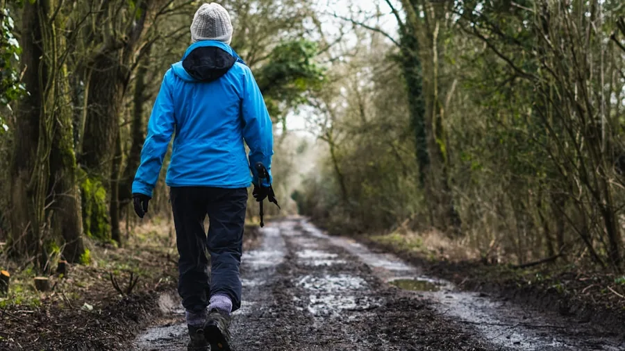 Hiker wearing durable rain jacket on wet mountain trail during rainfall
