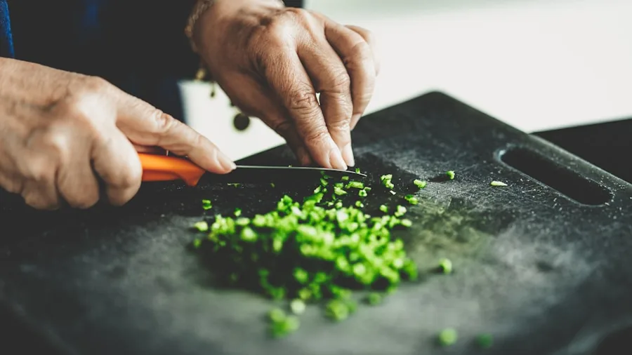 Home cook mincing garlic and chopping fresh vegetables on wooden cutting board in bright kitchen