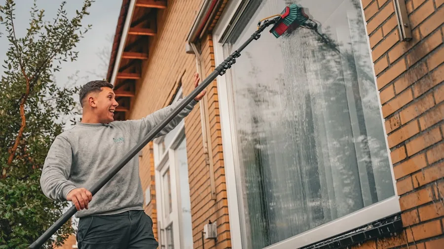 Homeowner spraying water on house exterior during cleaning day