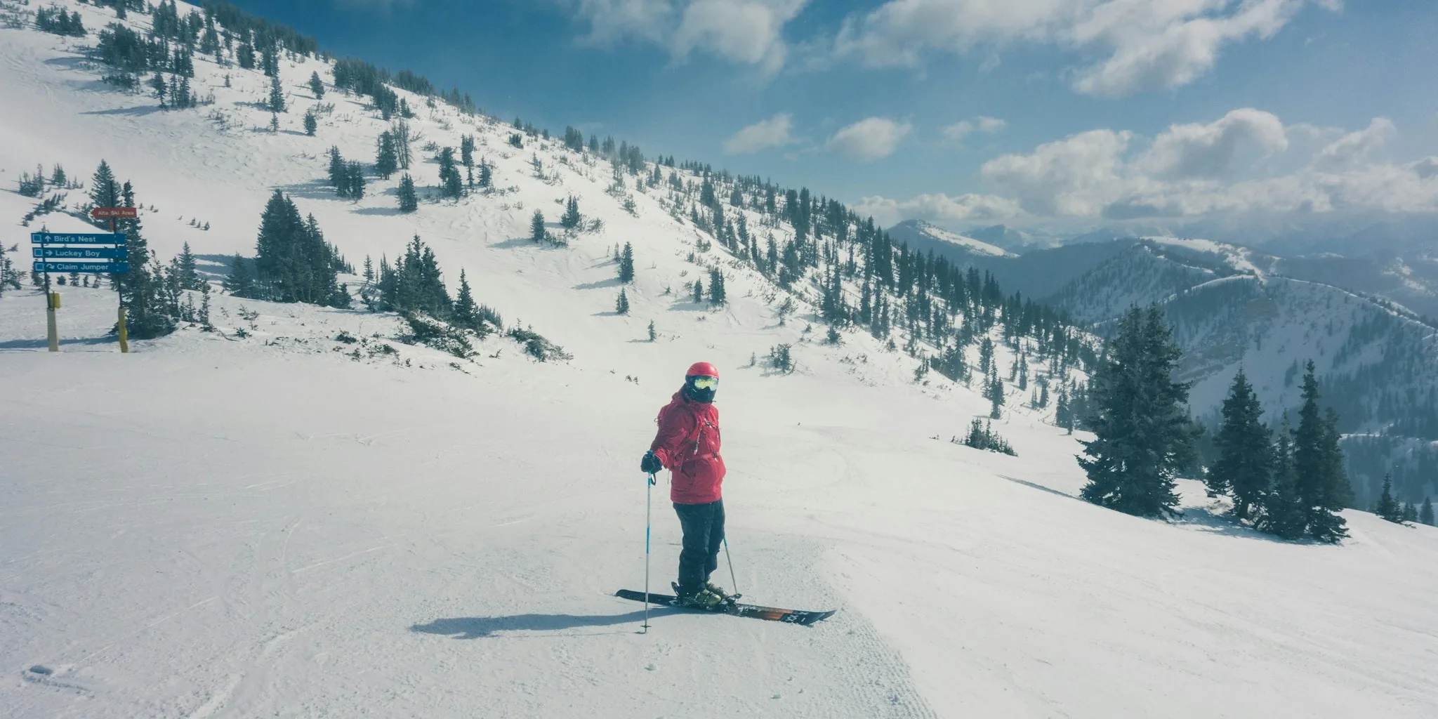 Male skier in winter jacket descending snowy mountain slope in bright daylight