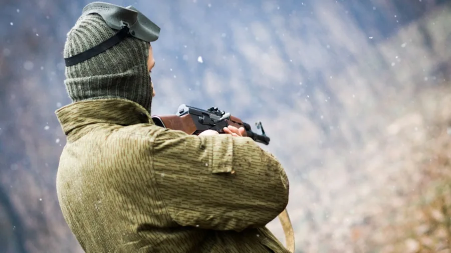 The %product_count% Best Hunting Boots for Men 4 Man in winter hunting gear standing alert in snowy forest landscape during cold weather