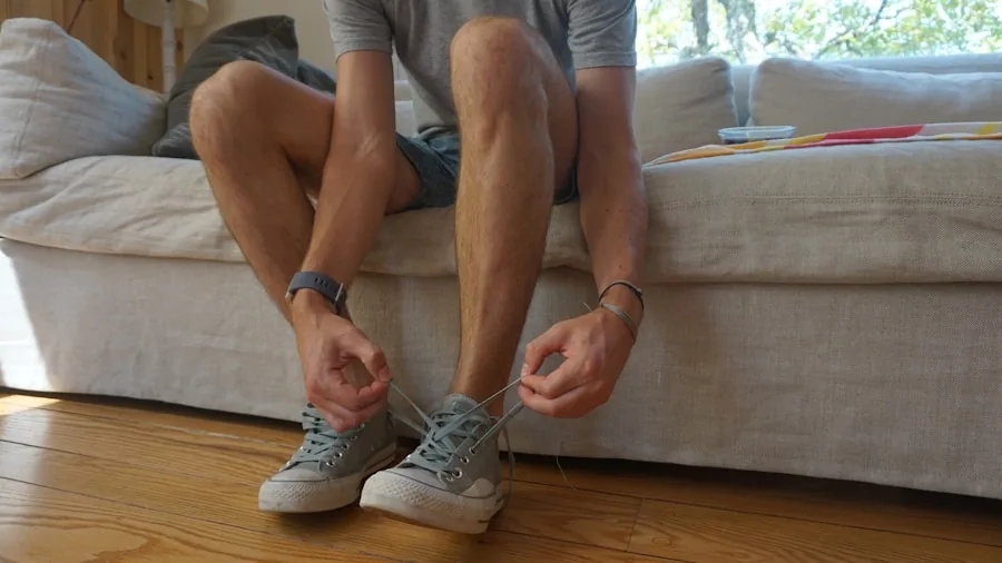 Man sitting while putting on socks before trying on walking shoes, natural daylight indoors