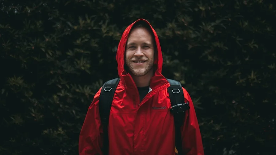 Man wearing rain jacket hiking through wet forest during rainfall