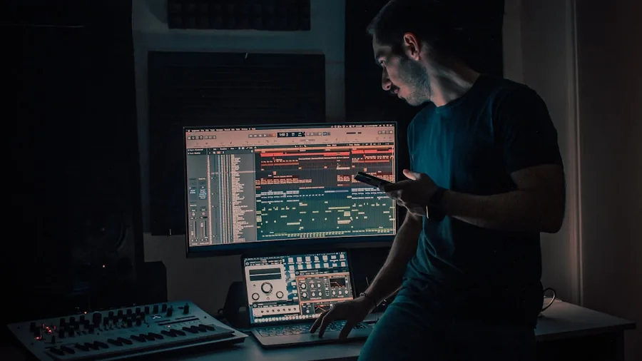 Music producer working on laptop at desk with headphones and audio equipment in professional studio setup