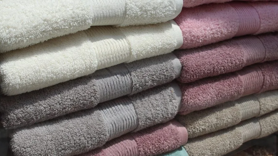 Organized bathroom shelf with folded towels and linens, showcasing proper storage and home organization