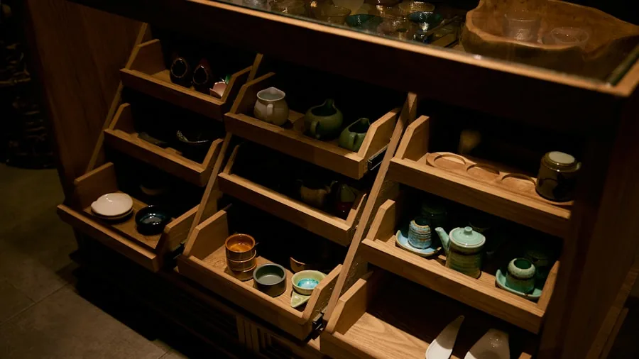 Organized tea storage containers and jars arranged on a wooden shelf in natural light