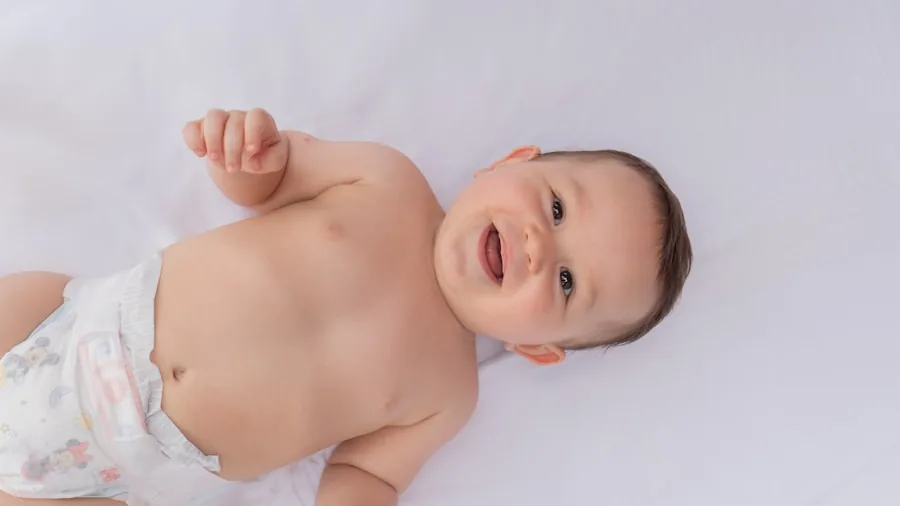 Parent carefully fitting diaper on infant to ensure proper waistband placement and leg cuff alignment
