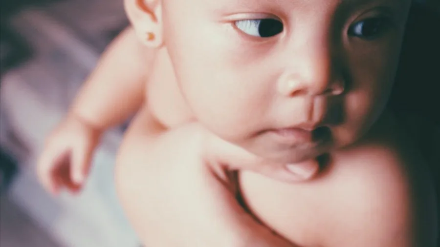 Parent gently touching baby's soft skin during diaper change, showing tenderness and comfort care
