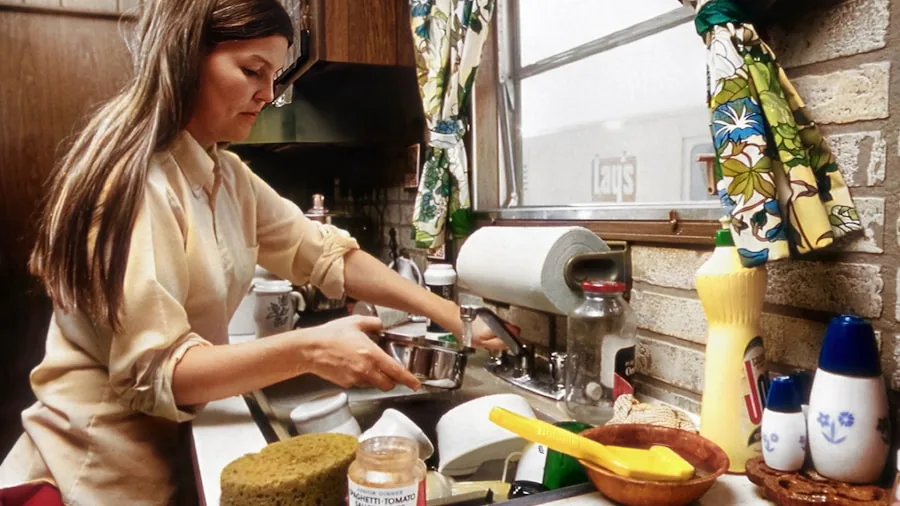 Parent washing breast pump components in kitchen sink with care and attention