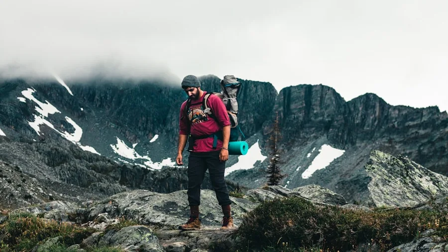 Person adjusting backpack straps while standing on a mountain trail during daytime