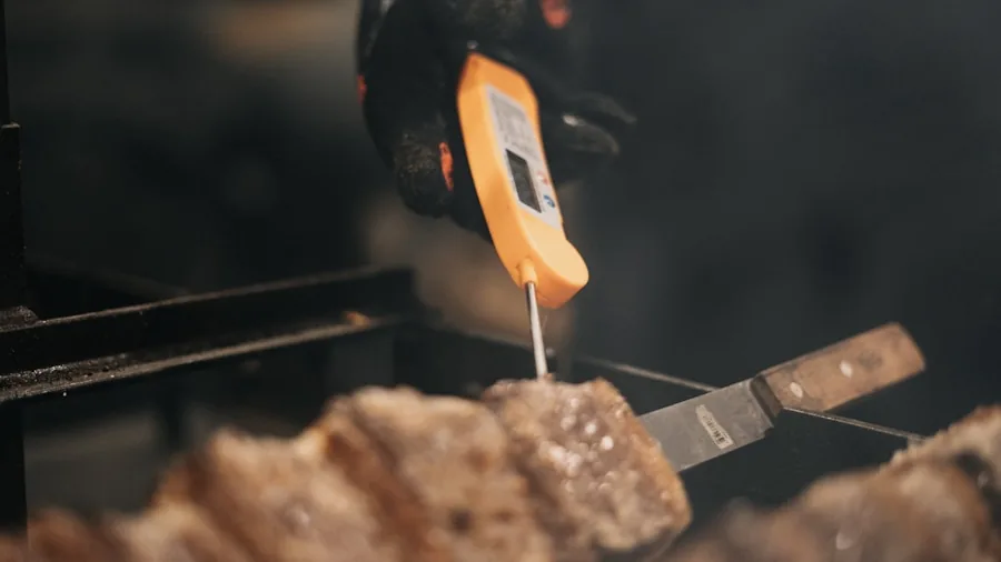 Person adjusting digital controls on modern outdoor grill while preparing food