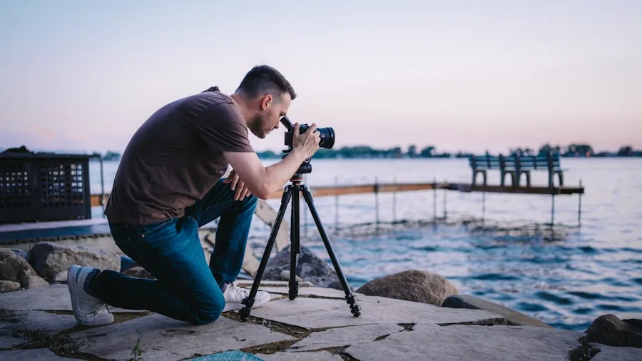 Person adjusting tripod legs on uneven ground for stable video recording outdoors
