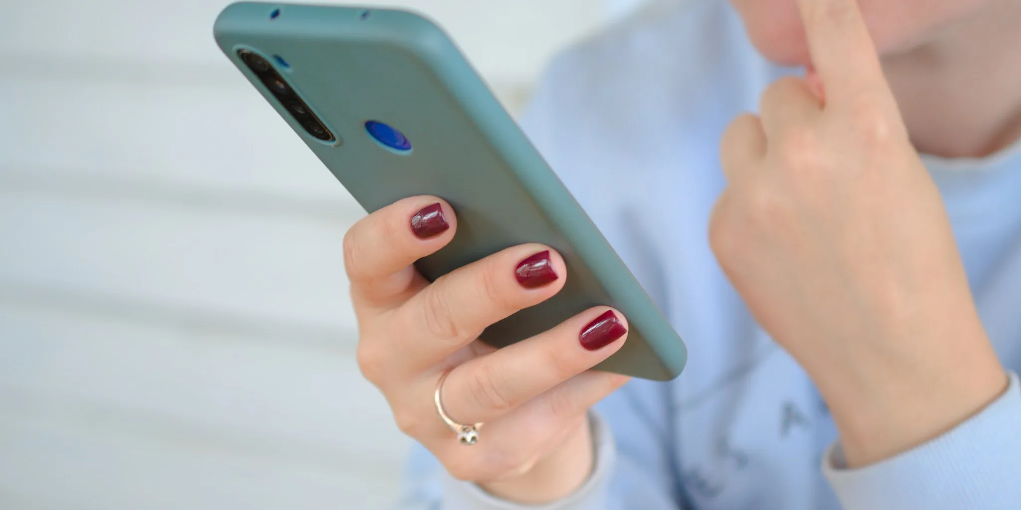 Person applying protective screen film to smartphone with careful precision