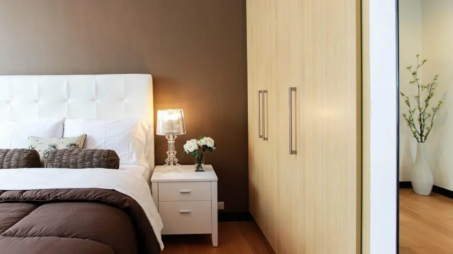 Person arranging shoes in organized closet space with natural lighting and wooden floors
