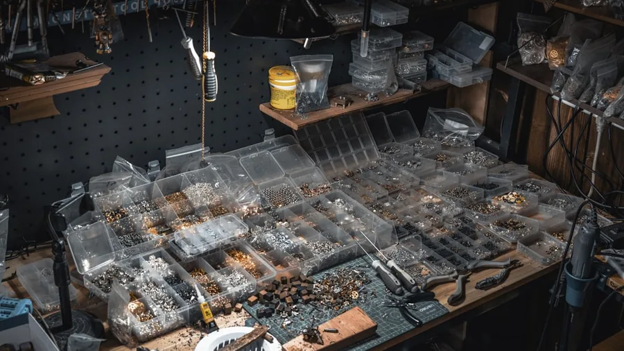 Person arranging various hand tools on a wooden workbench during home repair project