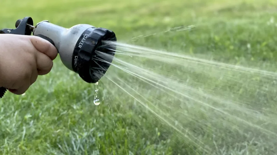 The %product_count% Best Sprinklers 5 Person attaching garden hose connector to outdoor watering equipment in residential yard