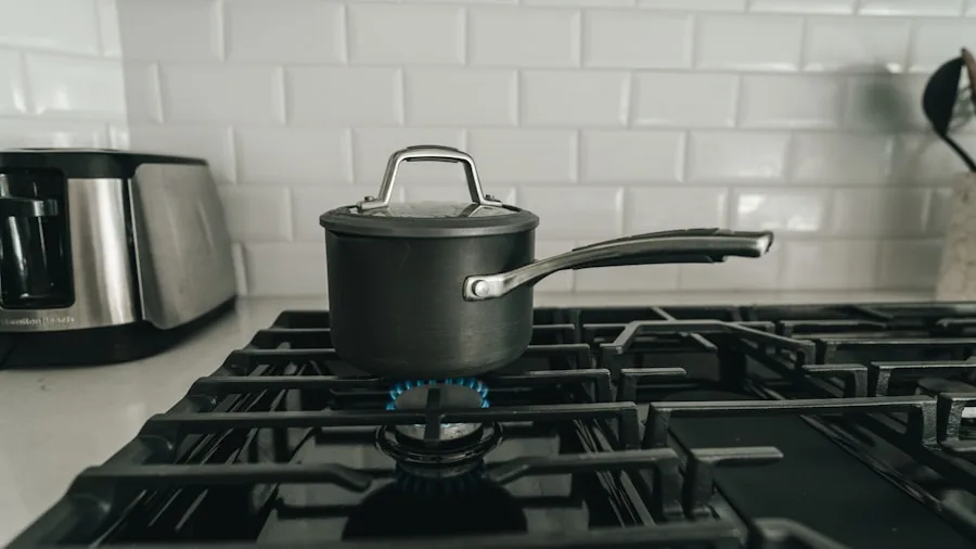 Person boiling water on stovetop in modern kitchen for cooking