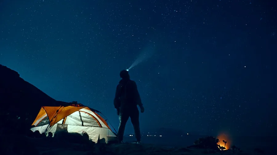 Person camping outdoors at night with tent illuminated, planning power needs for overnight trip