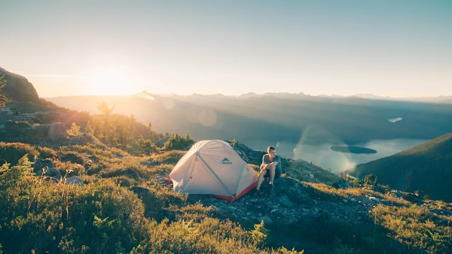 Person camping outdoors charging devices with portable power during evening adventure