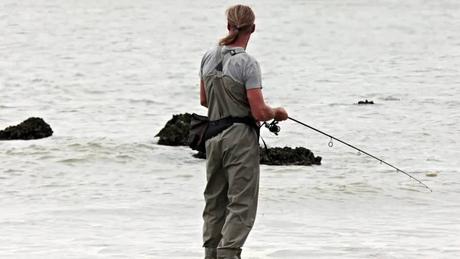 The %product_count% Best Kayaks for Fishing 2 Person casting a fishing rod from a wide stable kayak on calm water